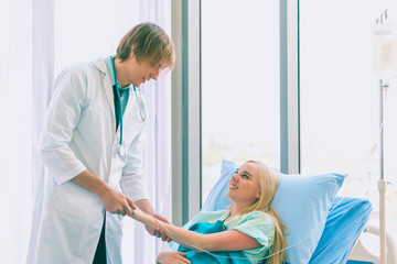 Obraz premium Asian young male doctor being injecting a young woman patient, who shows anxious facial expression and lying in bed In the room to treat the illness better.