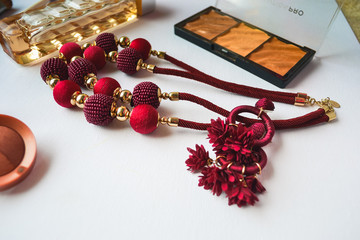 UK, Hove, 7/12/2019: Layout of perfume Boss, blush, necklace in burgundy color (made of threads), makeup brushes and earrings in the shape of flowers
