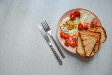 Simple breakfast, top view: fried eggs, toast, cheese, cherry tomatoes
