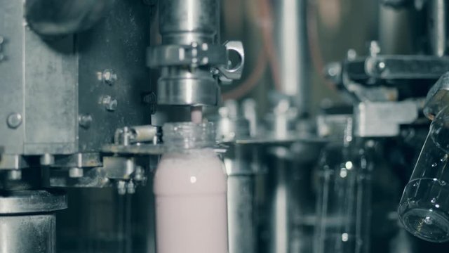 Factory machine fills bottles with yogurt. Automated production line at a food factory.