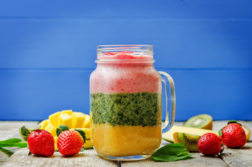 Mango Spinach strawberry kiwi banana smoothie with fresh fruit slices