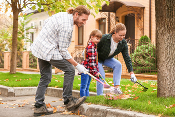 Family cleaning up autumn leaves outdoors