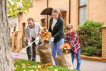 Family cleaning up autumn leaves outdoors