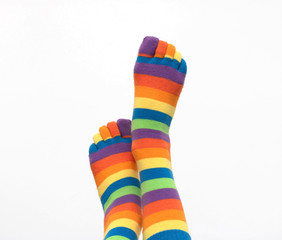 Female legs in colored socks raised to the top on a white isolated background