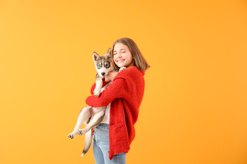 Cute teenage girl with funny husky puppy on color background