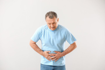 Mature man suffering from abdominal pain on white background