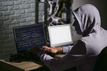 Professional hacker using laptop in dark room