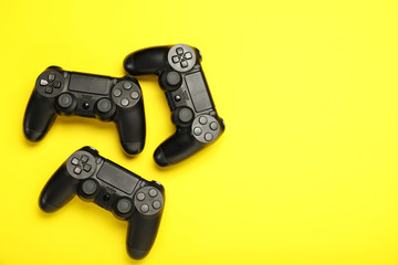 Modern game pads on color background