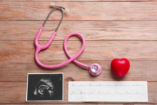 Stethoscope, heart, ultrasound image and cardiogram on wooden background