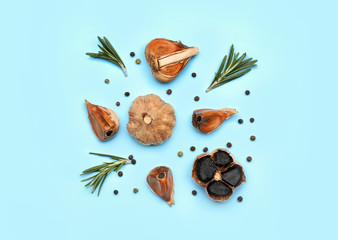 Composition with black garlic and spices on color background