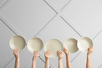 Hands with clean plates on light background