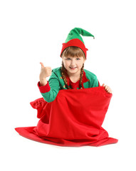 Little elf kid sitting in Santa Claus bag and showing thumb-up gesture on white background