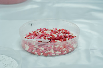 Selective focus extreme close up shot of colorful heart shaped confetti in plastic transparent box. Valentine's day decoration concept.