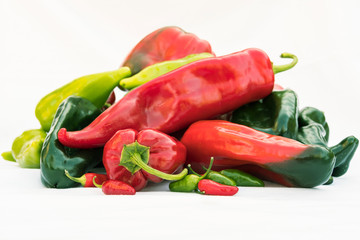 A pile of assorted peppers lying flat against a white background