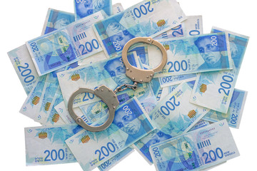 Handcuffs on Israeli money isolated on a white background. The new Israeli money bills (banknotes) of 200, shekel. Police handcuffs. Financial crime, dirty money and corruption concept.  