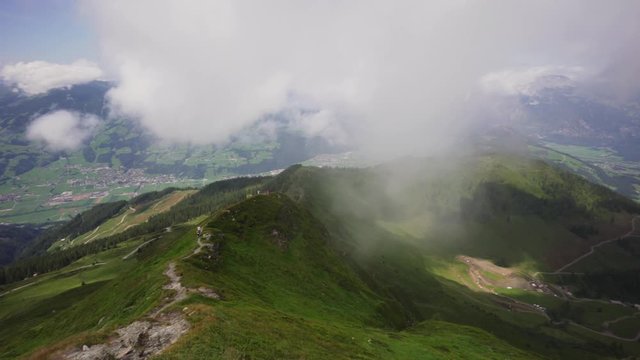 Pan left to right, capturing the beautiful mountains of Alpbach With clouds hanging over the valley.