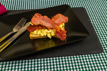 Breakfast of bacon and egg on toast.