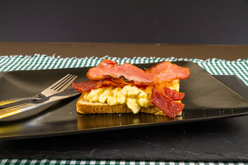 Breakfast of bacon and egg on toast.