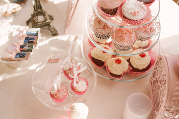 Colorful white and pink cupcakes decorated on the table for the wedding celebration of love, with cherries, cream and icing as decorations, a sweet alternative to the traditional wedding cake