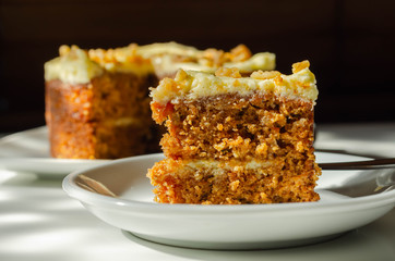 Sliced carrot cake filled and topped with cream cheese buttercream and decorated with walnuts