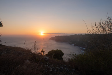 Orange Sunset Over The Ocean With Island Outcrops and Clouds At Manta Point, Nusa Penida, Bali, Indonesia