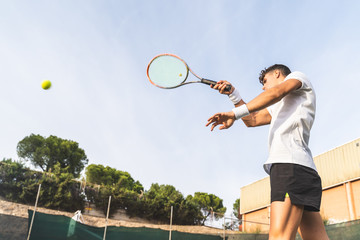 Young Man Playing Tennis Outdoors.