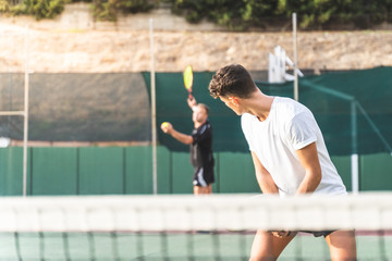Two Men Playing Tennis as a Team Outdoors.