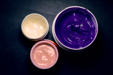 three jars of different colored face cream