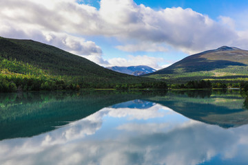 Reflection of mountains and clouds on still alpine lake