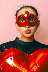 Woman wearing masquerade mask and holding heart shaped air ballon. Valentines Day, Birthday, Anniversary, Festive, Ball celebration concepts