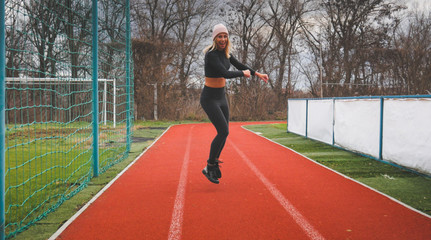 Training young woman in autumn stadium.  Run. Moment of jumping 
