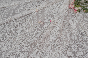 White wooden background with white spring flowers roses and lace ribbon. Happy womans day. The texture of lace on wooden background.