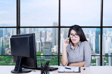 Asian businesswoman calling someone while working