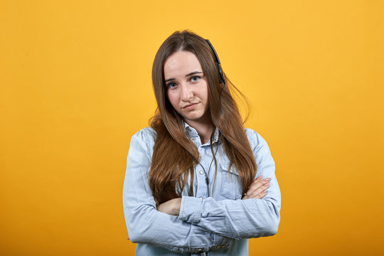 Unhappy attractive caucasian lady wearing fashion shirt isolated on orange background in studio keeping hands crossed on chest, looking at camera. People emotions, lifestyle concept.