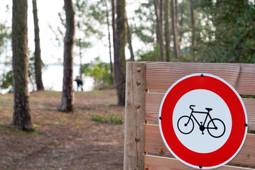white with red border round road sign No Cycling on a blurred park forest path way background of sky trees