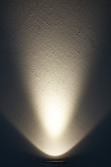 Eine helle Lampe erzeugt einen Lichtstrahl auf einer Wand.