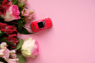 little red toy car carries a bouquet of pink flowers on a pink background.