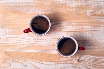 Two cups of coffee on a light brown table. Directly above