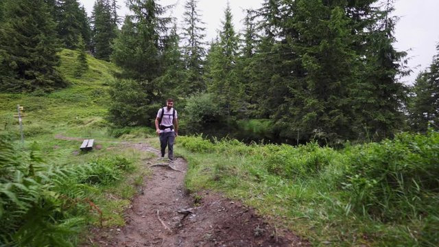 Man hiking alone in the middle of the mountain in Tirol. Steady shot, walking past camera.
