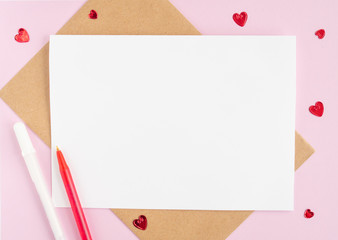 Minimalistic card mockup with envelope, postcard, pen, red hearts on  pink background. Flat lay, top view, copy space. Valentines day concept.