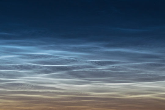 Close up of NLC: noctilucent clouds. Beautiful waves and ripples of silvery blue night shining clouds around midnight.