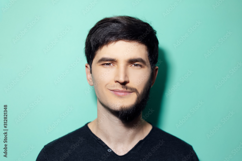 Wall mural Studio portrait of young man with half shaved face on background of aqua menthe color.