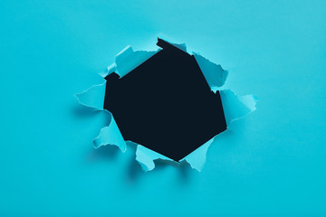 Torn hole in blue paper, ripped edges