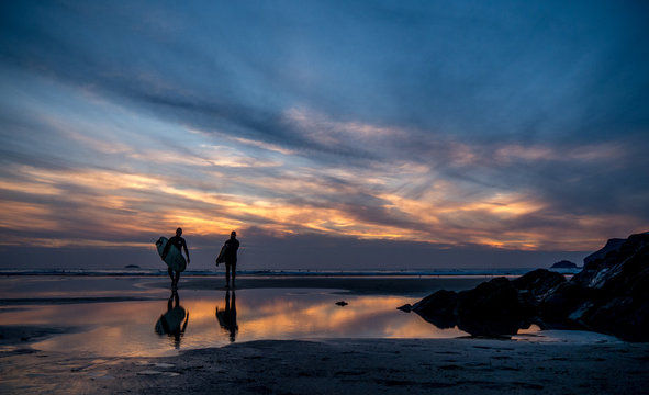 Silhouette of Surfers on the beach at sunset