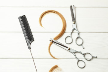 Question mark made of curl hair. Concept of how to choose a hairstyle or hairdresser. White wood background with hair and thinning scissors