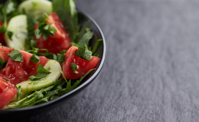 Salad with Tomatoes, Cucumber and Rocket on stone Background. Healthy Snack Idea. Close up. Copy space.