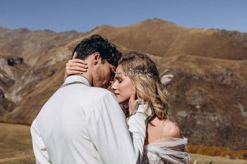 Bride in love on the top of the mountain: wedding photo shoot under a stylish arch, attractive man in a national Georgian costume and bride in a sophisticated dress