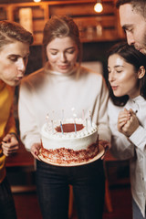 Surprise for her. Group of happy people celebrating birthday party with friends and smiling during party. Smiling attractive girl holding a cake in her hands