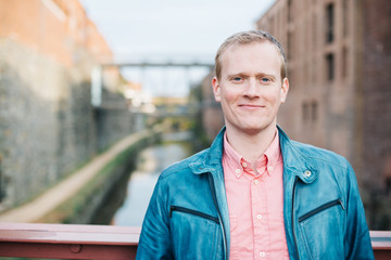 Handsome smiling caucasian man, stylishly dressed head and shoulders portrait looking confident at the camera standing on a bridge over a canal in Georgetown, Washington DC.  - 312826356