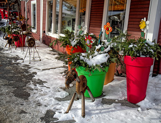Country store's outside metal art including large planters of flowers inviting guests into the store during the winter holidays.